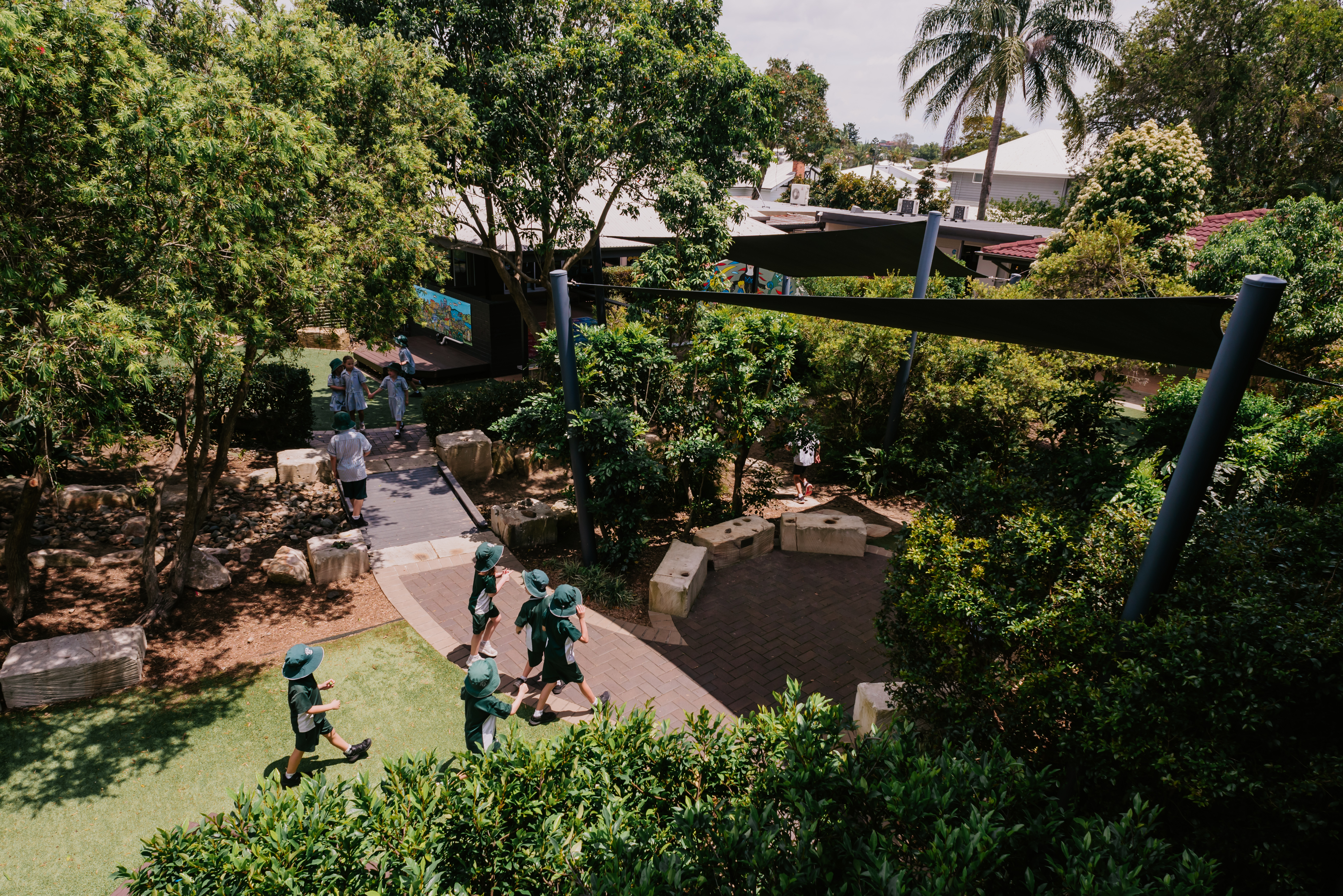 Students walking through landscaped school grounds, highlighting outdoor learning spaces and a natural school environment