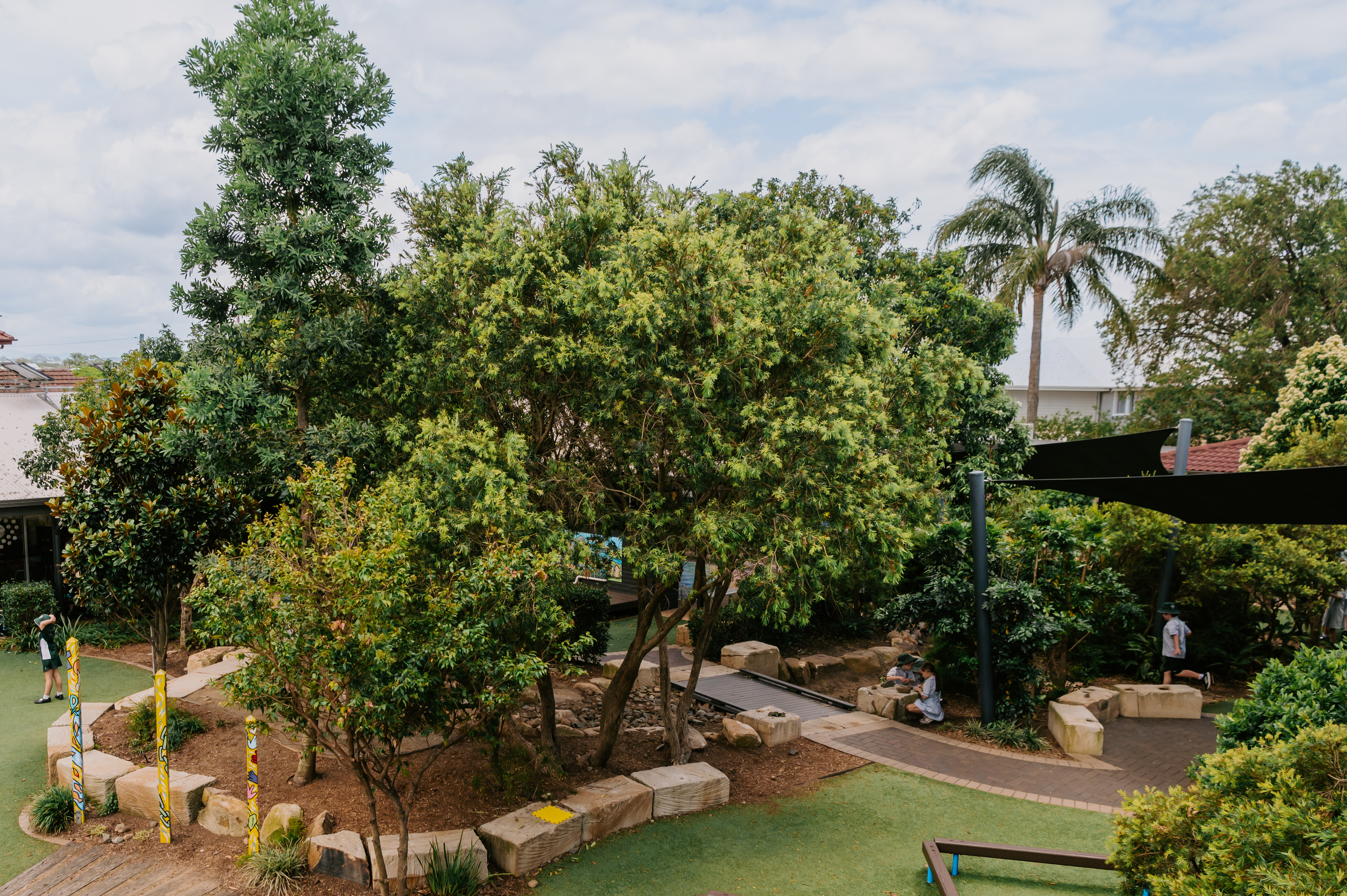 Wide view of the school grounds with shaded seating areas and pathways, representing a welcoming and well‑planned learning environment