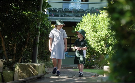 Students walking along a shaded school pathway, representing everyday learning, friendship and a supportive primary school environment
