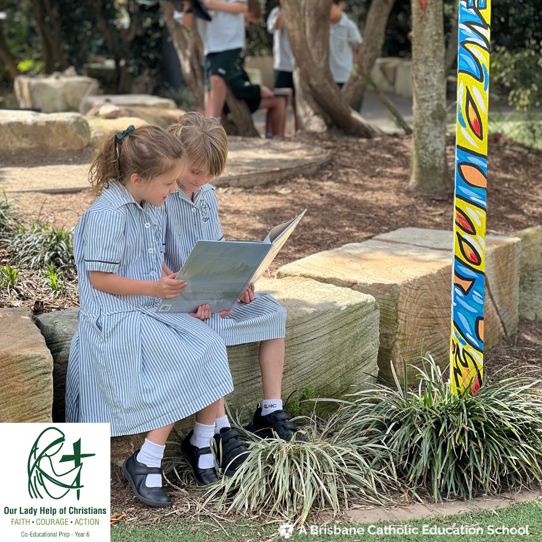 Students reading together outdoors on school grounds, highlighting shared learning, literacy development and a supportive primary school environment